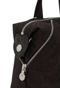 Black fabric handbag featuring a textured pattern, silver zipper hardware, and a black leather accent with a button detail.