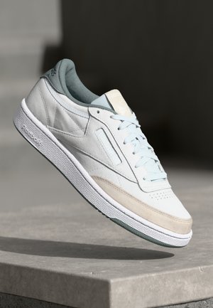 Lyseblå lærersneaker med en kremfarget og beige semsket tå, hvite lisser, teksturert såle og akvamarin aksenter. Logo prydet på tungen.