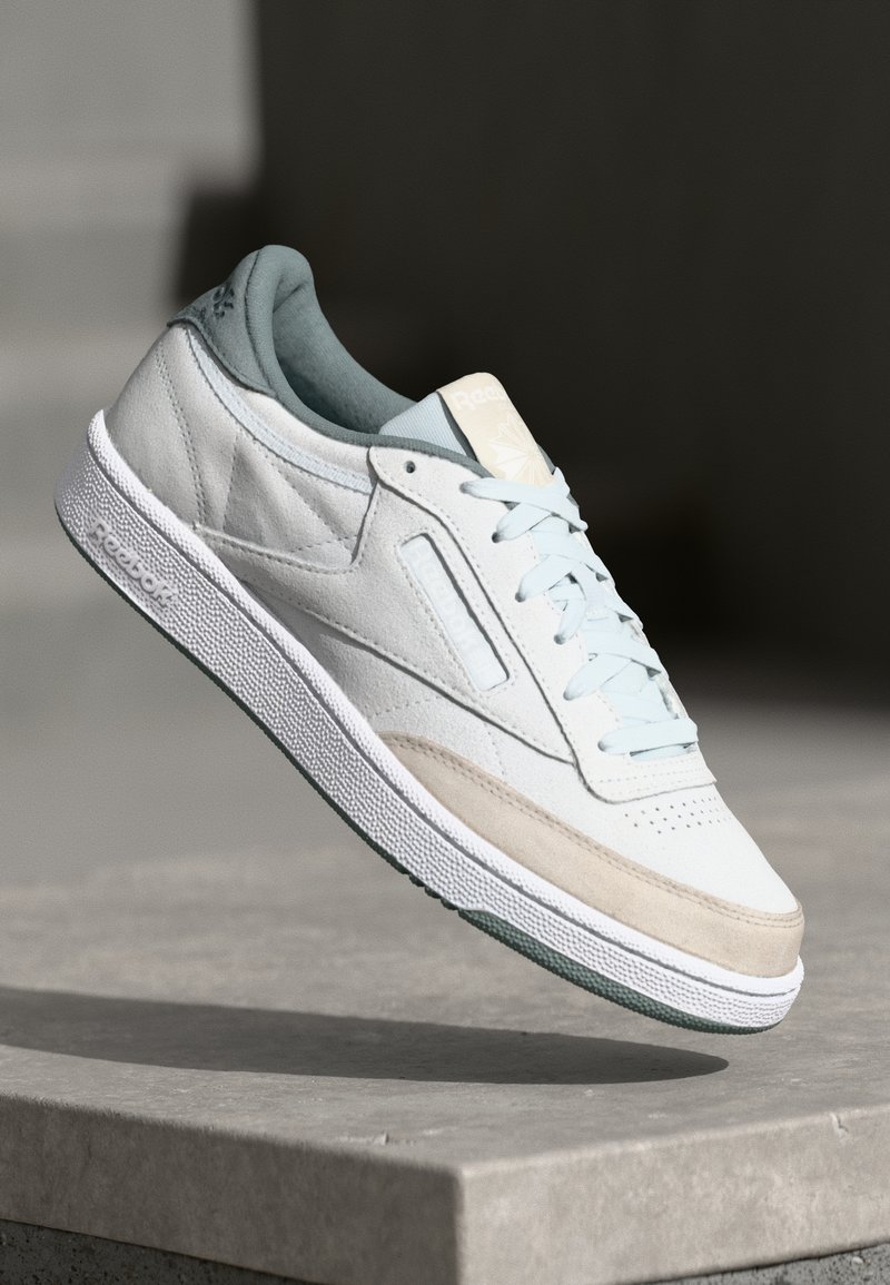 Jasnoniebieskie skórzane sneakersy z kremowym i beżowym zamszowym noskiem, białymi sznurówkami, teksturowaną podeszwą i turkusowymi akcentami. Logo wytłoczone na języku.