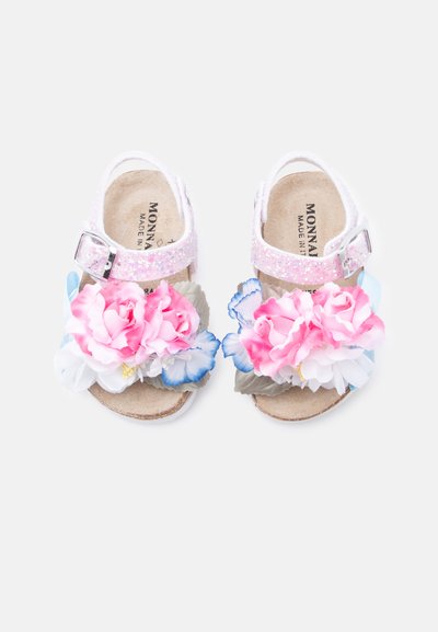 Ροζ σανδάλια με γκλίτερ και αγκράφα, διακοσμημένα με υφασμάτινα λουλούδια σε ροζ, άσπρο και μπλε. Μαλακή εσωτερική επένδυση και επίπεδες ταμπά σόλες.