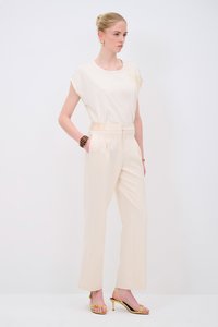 Beige kortmouwtop, crèmekleurige op maat gemaakte high-waist broek en gele sandalen met bandjes. Gladde stof met subtiele textuur, strakke lijnen en zakken.