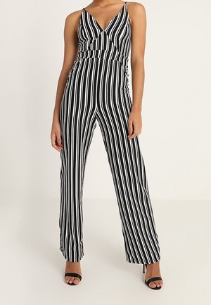 Musta-valkoiset raidalliset haalari ohutolkaimilla, kietaisutyylinen yläosa ja leveät lahkeet. Suhteellinen kangas yhdistää modernin siluetin.