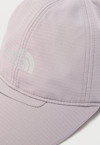 Ανοιχτό μωβ καπέλο με υφή στην επιφάνεια. Διαθέτει γείσο με ραφές και λευκό λογότυπο της The North Face στο μπροστινό πάνελ.