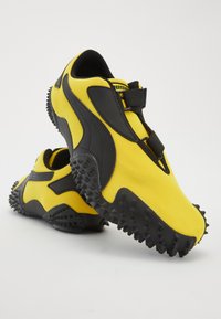 Yellow synthetic running shoes with black accents, textured mesh upper, padded collar, and rugged spike tread for traction.
