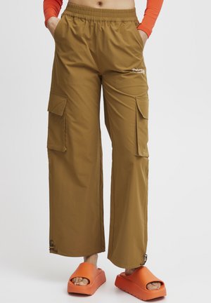 Light brown cargo pants with an elastic waistband, two side pockets, and adjustable hem. Paired with orange platform sandals.