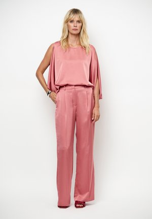 Rosa Satin-Outfit mit ärmellosem Oberteil mit drapierten Seiten und maßgeschneiderten, weit geschnittenen Hosen. Glatte Textur mit sanftem Glanz.