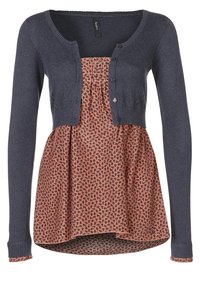 Námořnický pletený cardigan přes květinovou blůzu s potiskem v odstínech broskve a černé. Má knoflíky a rozšířený spodní lem.