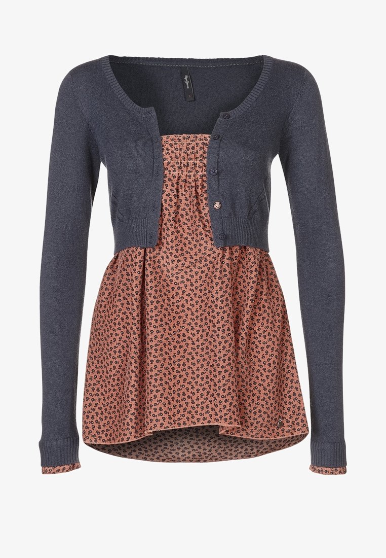 Námořnický pletený cardigan přes květinovou blůzu s potiskem v odstínech broskve a černé. Má knoflíky a rozšířený spodní lem.