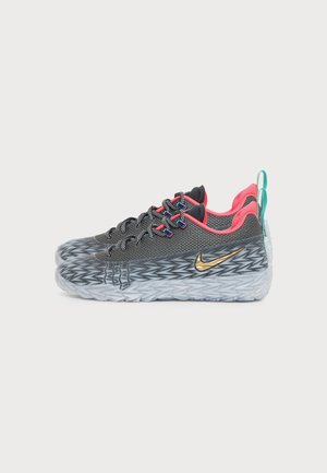 Baskets Nike grises et noires avec doublure intérieure rose, logo doré, semelle texturée et languettes bleues, affichées côte à côte sur fond blanc.