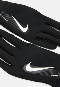 Gants thermiques noirs avec une finition texturée, arborant un logo et des graphismes blancs de Nike à l'arrière, conçus pour la chaleur et l'adhérence.