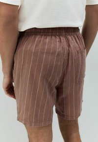 Bruine gestreepte shorts met een elastische tailleband en één achterzak, gemaakt van lichtgewicht stof met een zachte textuur.