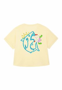 Geel T-shirt met korte mouwen met een blauw geborduurd haaienafbeelding met een roze object in zijn mond, verfraaid met een zon en kleurrijke details.