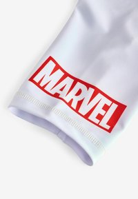Fehér textilujj, amelyen jól látható piros "MARVEL" logó található, sima felülettel és megerősített varrással az élein.