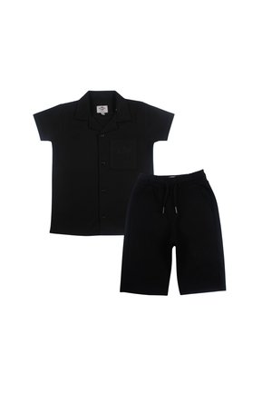 Chemise noire à manches courtes avec boutons, col et poche poitrine associée à un short noir à cordon à hauteur du genou.