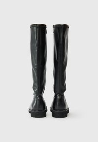 Bottes noires montantes en cuir lisse avec un bout arrondi, des détails de couture apparente, une fermeture à glissière latérale et une semelle en caoutchouc robuste.