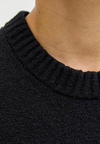 Mustra musternik kaelus, millel on soonik tekstuur ja pehme kangas, tihedalt lõigatud, et rõhutada kaelaosa ja materjali üksikasju.