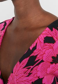 Zwart en roze stoffen met bloemenpatroon met een gladde textuur, met een hoekige halslijn en gedurfde, grote bloemontwerpen.