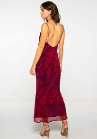 Vestido largo rojo con estampado floral, tirantes finos y espalda descubierta. Tela suave y ligera con una silueta ajustada.
