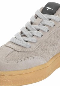 Hellgraue Wildleder-Sneaker mit strukturiertem Seitenpanel, flachen Schnürsenkeln und Sohle aus Gummi. Schwarze Akzente auf der Zunge mit kleinem Logo.