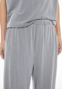 Grau geripptes Stoffoberteil und lockere Hosen mit elastischem Bund und seitlichen Taschen, die eine weiche Textur und ein lässiges Design präsentieren.