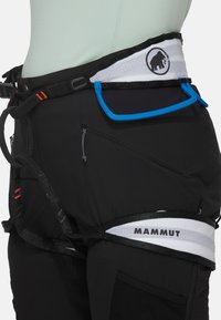 Zwarte klimharnas met verstelbare riemen, blauwe accenten en een prominent wit Mammut-logo. Bevat meerdere gear loops en zakken.