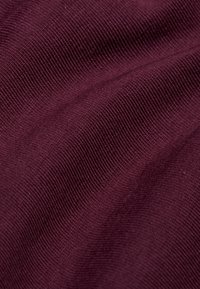 Bordowy elastyczny materiał o prążkowanej fakturze, z gładkimi i subtelnymi falami, wskazujący na miękki i elastyczny materiał.