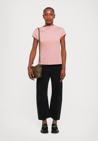 Light pink short-sleeve top, black wide-leg pants, black loafers, and a small olive green crossbody bag. Simple design, smooth texture.