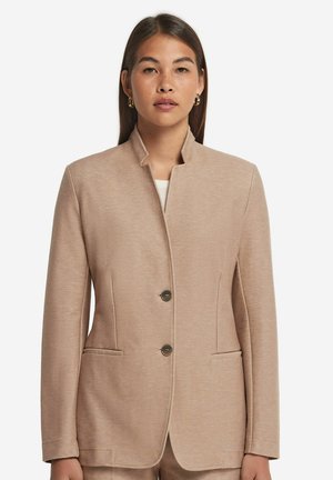 Blazer beige chiaro con colletto alto, dotato di due bottoni metallici, due tasche frontali e un tessuto testurizzato per un effetto di maggiore profondità.