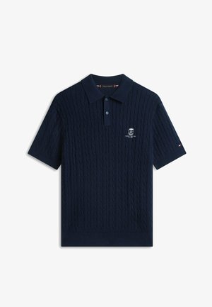 Polo de manga corta color azul marino con patrón de punto trenzado, tapeta de dos botones y pequeño logo bordado en el pecho y la manga.