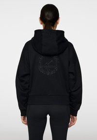 Schwarzer Kapuzenpullover mit einem verkürzten Design, der auf dem Rücken ein großes geprägtes Berglogo und gerippte Bündchen sowie einen gerippten Saum aufweist.