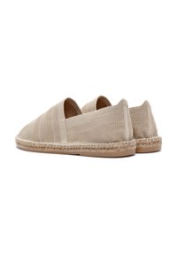 Scarpe slip-on beige realizzate in tessuto testurizzato con dettagli intrecciati lungo la suola e un design flessibile per il comfort.