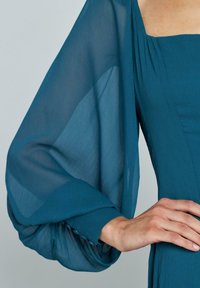 Türkises Kleid mit quadratischem Ausschnitt und transparenten Puffärmeln, aus strukturiertem Stoff und mit Knopfakzenten an den Bündchen.
