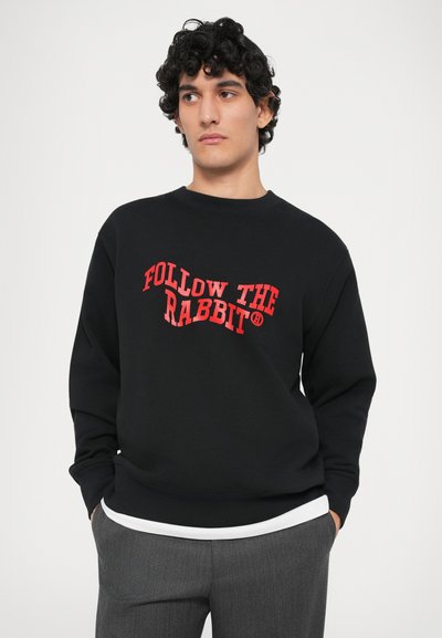 Sort sweatshirt med rund hals, med fed rød tekst "FØLG KANINEN". Blødt stof, lange ærmer og en afslappet pasform.