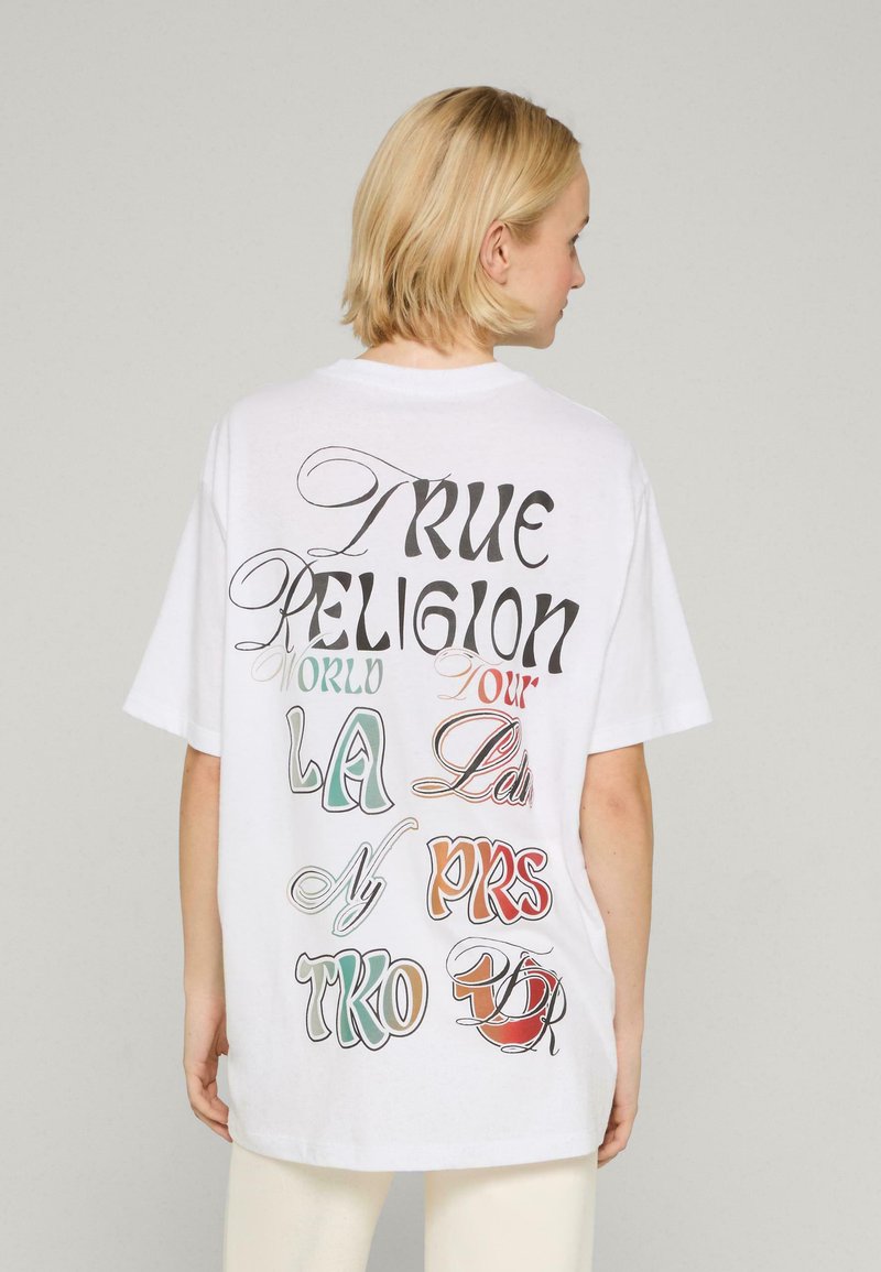 Biała, oversize'owa koszulka z krótkim rękawem, z klasycznym okrągłym dekoltem, z kolorowym graficznym napisem na plecach: "TRUE RELIGION WORLD TOUR LA NYC PRS TKO."