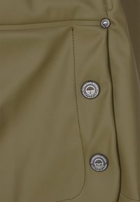 Olīvu zaļš ūdensizturīgs audums ar trim metāla pogām, uz kurām ir logo, redzamajām šuvēm un sānu kabatas detaļu.