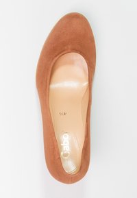 Chaussure plate en daim marron avec un bout rond et une doublure intérieure exposée. Présente un logo Gabor doré sur la semelle intérieure.