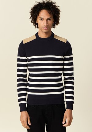Maglione a righe navy con righe orizzontali bianche, dettagli beige sulle spalle, colletto e polsini a costine, texture lavorata a maglia e design aderente.