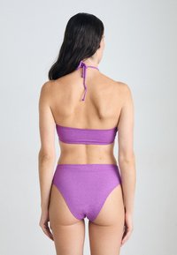 Πορφυρό σετ μπικίνι που περιλαμβάνει μπικίνι μπάντεο με δεμένο λαιμό και ψηλόμεσα σλιπ, φτιαγμένο από γυαλιστερό, υφασμάτινο υλικό.