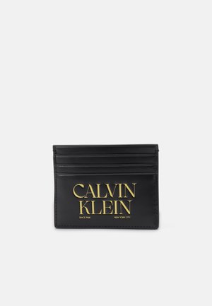 Mustast nahast kaarditaskul on kuus pesat, kuldse embossed "CALVIN KLEIN" logo ja lisatekst "SINCE 1968 NEW YORK CITY" allosas.