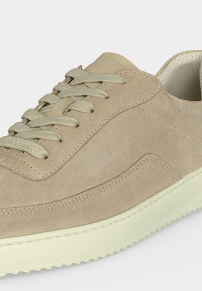 Μπεζ σουέντ αθλητικό παπούτσι με κρεμ κορδόνια, επενδεδυμένη γλώσσα και εκρού υφασμένη λαστιχένια σόλα, εμφανιζόμενο σε κοντινή λήψη από πλάγια γωνία.