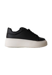 Baskets basses noires avec une épaisse semelle plateforme blanche et des lacets noirs, vues de profil sur fond blanc.