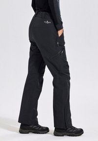 Schwarze Outdoor-Hosen mit geradem Schnitt, Reißverschlüssen an den Seiten und einem Logo am Bund. Strukturiertes Material und strapazierfähige Nähte.