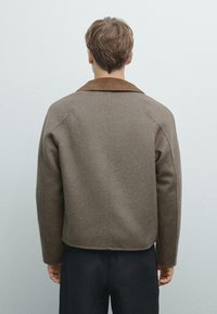 Brown wool blend jacket with a contrasting tan collar, featuring a boxy silhouette and minimalist design. Smooth texture, drop shoulders.
