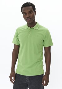 Grön polotröja i mjuk bomull, med krage, treknappsstängning, korta ärmar och en diskret logotyp på bröstet.