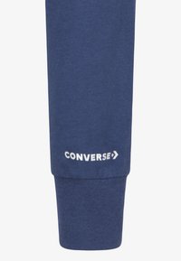 Maritieme sweatshirtmanchet gemaakt van een zachte katoenmix, met witte "CONVERSE" logo print en een steraccent. Gladde textuur en aangesloten ontwerp.