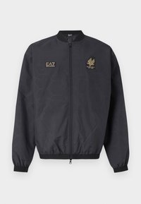 Μαύρο μπουφάν bomber με φερμουάρ, με ριμπ γιακά, μανσέτες και τελείωμα, με δύο χρυσά κεντημένα λογότυπα EA7 Emporio Armani στο στήθος.