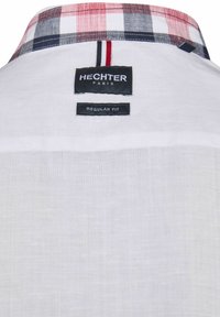 Weißes Hemd mit einem karierten Kragen in Rot, Blau und Weiß. Mit einem Etikett "HECKTER" und "REGULAR FIT." Glatte Textur.