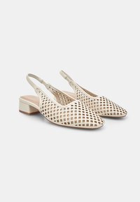 Zapatos blancos tipo slingback con un patrón de rejilla recortado y un tacón bloque bajo. Acabado liso y correa ajustable en el tobillo.