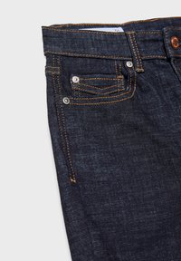 Ciemnoniebieskie dżinsy z pomarańczowymi przeszyciami, małą przednią kieszonką, metalowymi nitami i prostym krojem. Pas z etykietą rozmiaru.