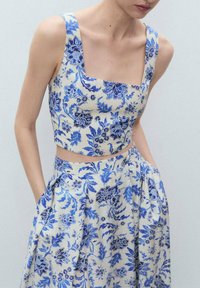 Floral Crop-Top und Rock-Set aus leichtem Stoff, mit einem blauen Blumenmuster auf cremefarbigem Hintergrund, quadratischem Ausschnitt und plissiertem Rock mit Taschen.